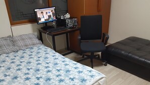 Un dormitorio con una cama, un escritorio con computadora, una silla y un sofá.