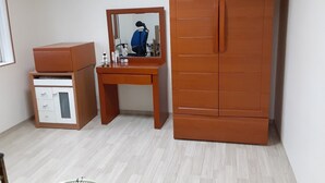 Una habitación pequeña con un armario de madera, un escritorio con espejo y un pequeño mueble.
