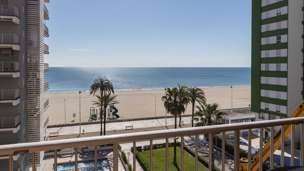 A view from a balcony overlooking a beach with palm trees, a pool, and a playground. - TRIANON, 5º-29 (Cullera)