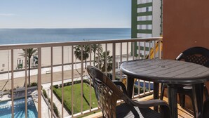 A balcony with a view of the beach and ocean. There is a table and chairs, and a pool is visible in the background. - TRIANON, 5º-29 (Cullera)
