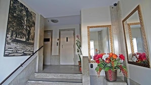 Una escalera que lleva a una habitación con un espejo grande y una planta en maceta con flores.