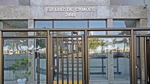 Entrada de un edificio con una reja metálica, una planta en maceta y un letrero que dice 'ED. LUIZ DE CAMOES 2440'.