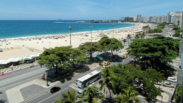 Una zona urbana frente a la playa, con un amplio paseo marítimo, una playa y edificios altos al fondo.