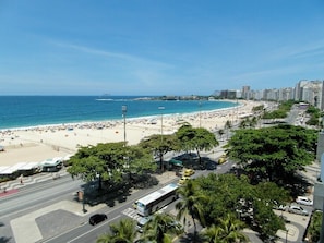 Ein städtisches Gebiet am Strand mit einer breiten Promenade, einem Strand und Hochhäusern im Hintergrund.