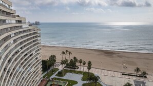 A beachfront hotel with a curved building, a sandy beach, and palm trees. - FLORAZAR 1, III-A 18-C (Cullera)