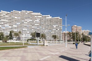 Un grand hôtel à plusieurs étages, doté d’une architecture moderne, avec une cour intérieure agrémentée de palmiers et d’une fontaine.
