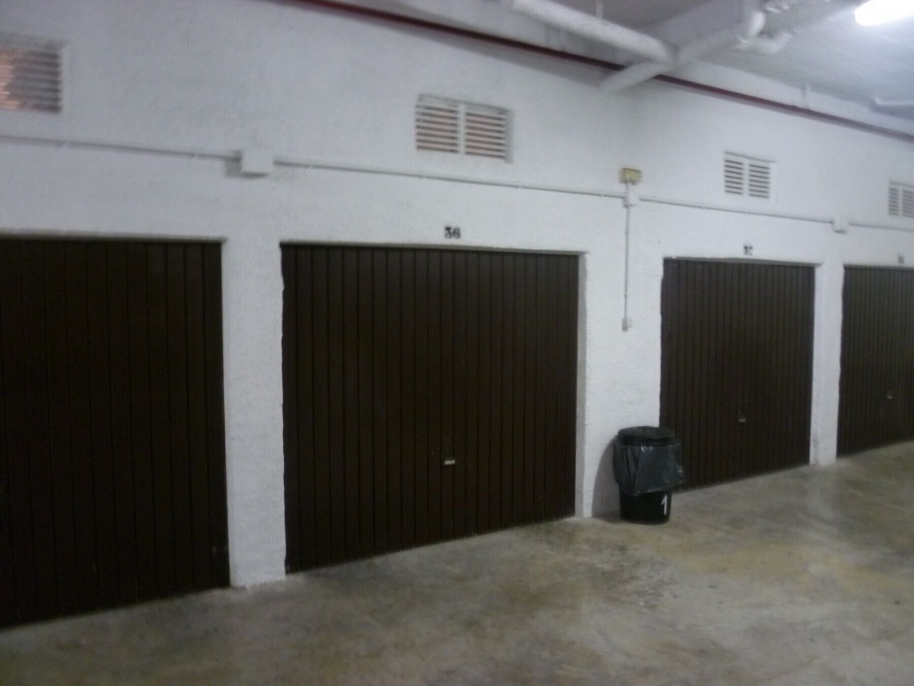 A row of closed, dark-colored doors with numbers on them, indicating a series of rooms or storage units.