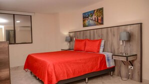 Un dormitorio con cama, mesita de noche, lámpara, un cuadro y espejo.