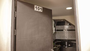 En stängd dörr med en skylt där det står ”101”, i ett rum med kakel på väggen bakom diskbänken och köksinredning.