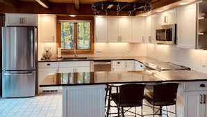 A modern kitchen with white cabinets, stainless steel appliances, and a large island with bar stools. - Luxury Lakefront: Hot Tub, Fireplace, Pet Friendly, Arcade, Watercraft, + more! (Lake Ariel)