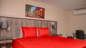 Een hotelkamer met een groot bed, twee nachtkastjes, een bureau, een stoel en een schilderij aan de muur.