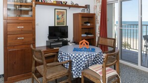 A room with a wooden desk, a television, and a table with a checkered tablecloth. - MONTEMAR, C-8º-22 (Cullera)