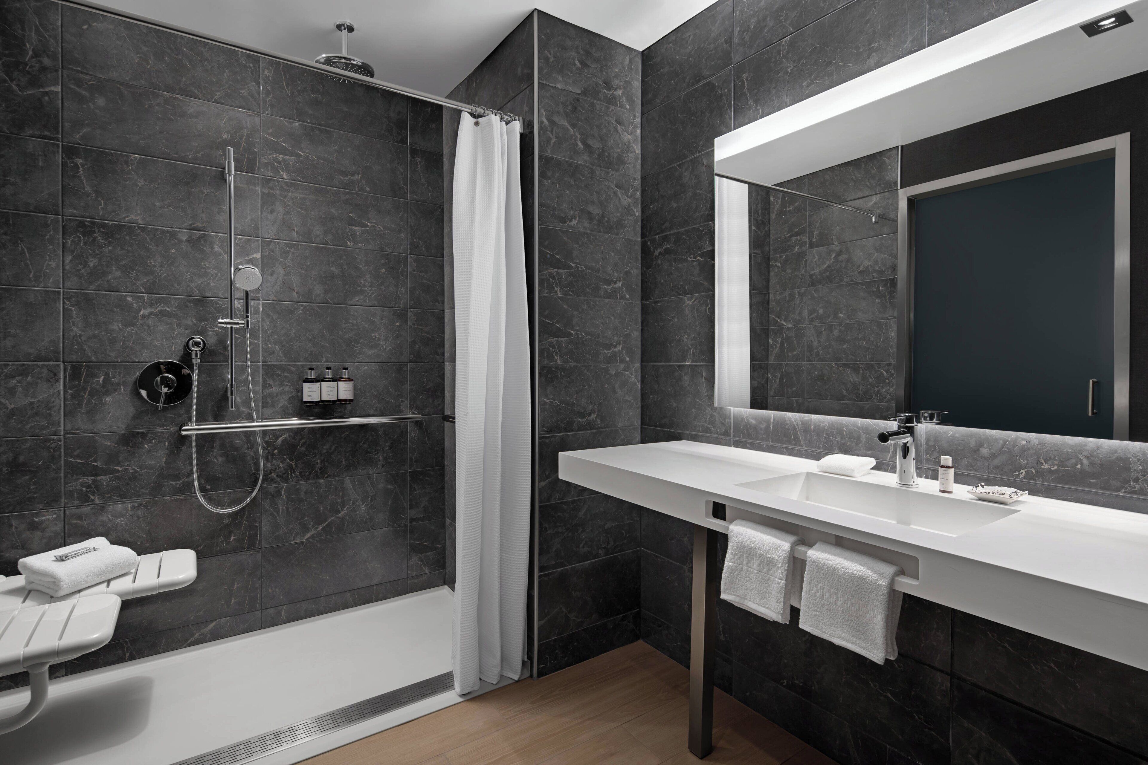 A modern bathroom with a shower, a sink, and a large mirror.