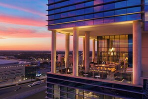 Un hotel moderno con un bar en la azotea, amplios ventanales y vistas a la ciudad.
