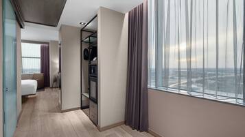 Een moderne hotelkamer met een groot raam, een bed, een bureau en een kledingkast.