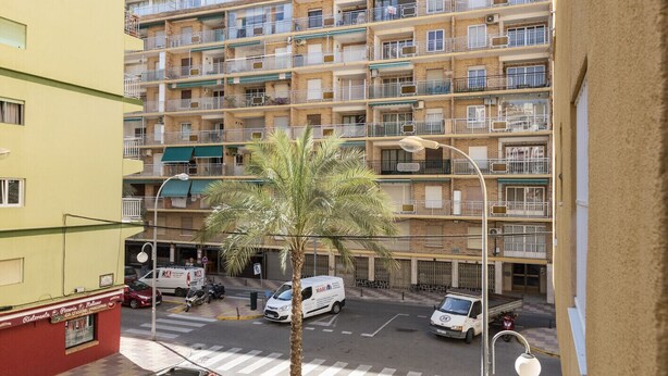 A multi-story residential building with balconies, a palm tree in the foreground, and parked vehicles. - MAR Y MONTAÑA, 2º-18 (Cullera)