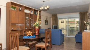 A living room with a dining table, chairs, a bookshelf, a sofa, and a TV. - MAR Y MONTAÑA, 2º-18 (Cullera)