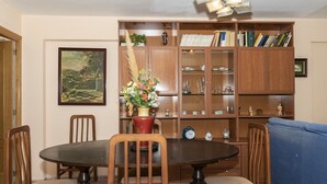 A dining area with a round table, chairs, a vase of flowers, and a bookshelf filled with books and decorative items. - MAR Y MONTAÑA, 2º-18 (Cullera)
