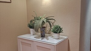 A corner cabinet with two potted plants on top, a wall-mounted light fixture, and a framed picture on the wall. - MARI CARMEN, 2º-8 (Cullera)