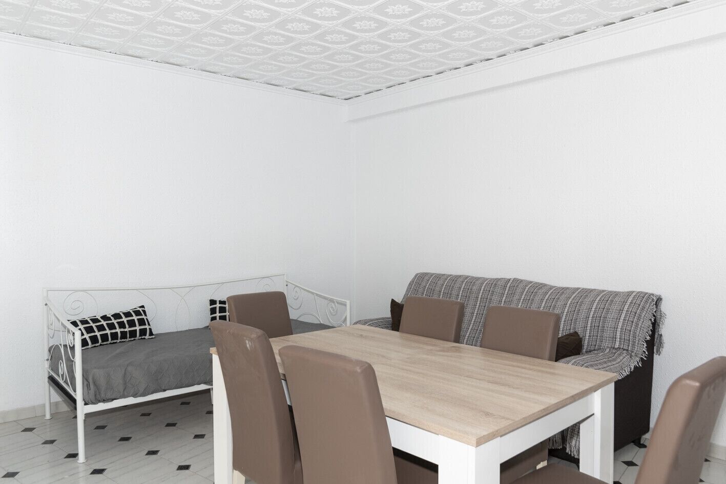 A room with a bed, a dining table, and chairs.
