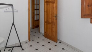 A room with a wooden door, a hanging clothes rack, and a tiled floor.