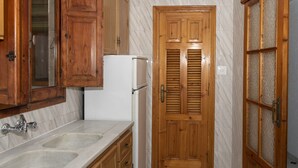 A kitchen with wooden cabinets, a white refrigerator, and a marble backsplash.