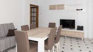 A modern living room with a dining table, sofa, TV, and a cabinet.