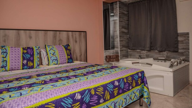 A bedroom with a large bed, a bathroom with a bathtub, and a shower area. - Hot tub studio Ground floor AC (Medellin)