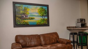 A brown leather sofa in a living room with a painting of a landscape on the wall. - Hot tub studio Ground floor AC (Medellin)