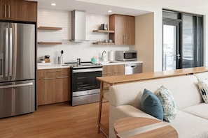 A modern kitchen with stainless steel appliances, wooden cabinets, and a wooden dining table. - Element by Marriott Nashville Vanderbilt West End (Nashville)