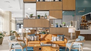 A modern living area with a sofa, chairs, a coffee table, and a bookshelf. - Element by Marriott Nashville Vanderbilt West End (Nashville)