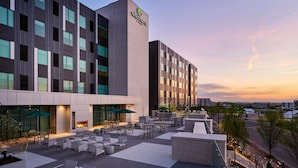 Un hotel con fachada moderna, zona de estar al aire libre y una chimenea visible.