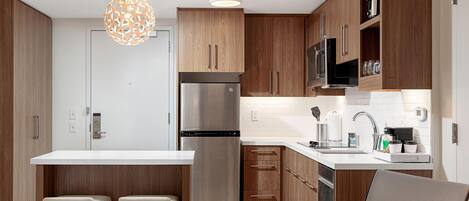 Een koelkast, een magnetron, een koffiezetapparaat/waterkoker, eettafels