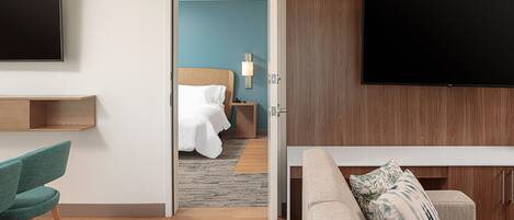 A hotel room with a bed, a TV, a desk, and a sofa.