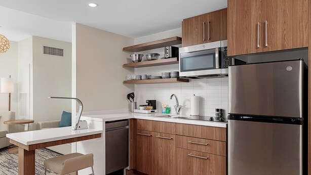 Una cocina moderna con armarios de madera, electrodomésticos de acero inoxidable y un taburete de bar.