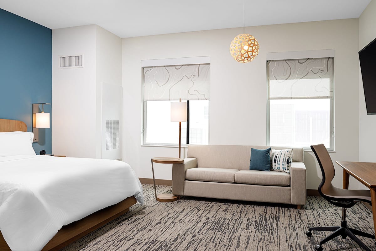 Een hotelkamer met een bed, een bank, een bureau en een stoel.