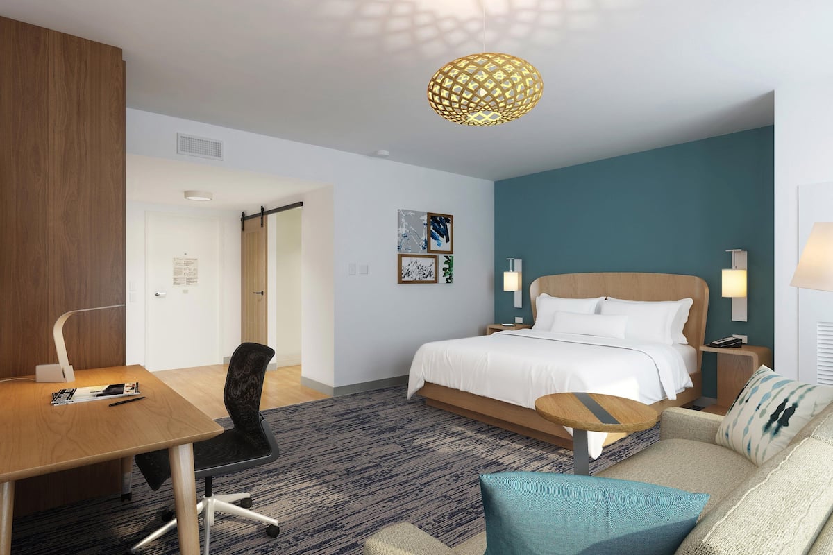 Een hotelkamer met een bed, een bureau, een stoel, een bank en een lamp.