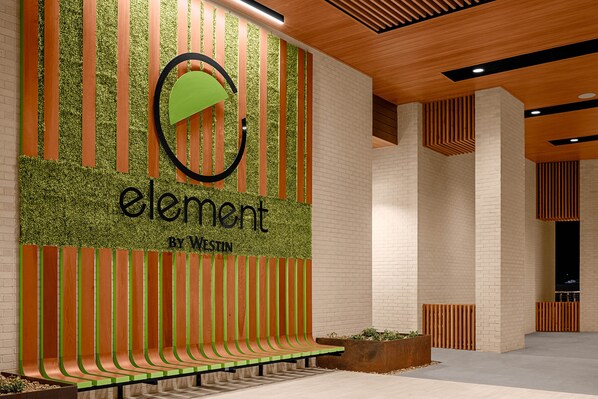 A modern interior with a green and orange wall design, a bench, and a wooden ceiling.