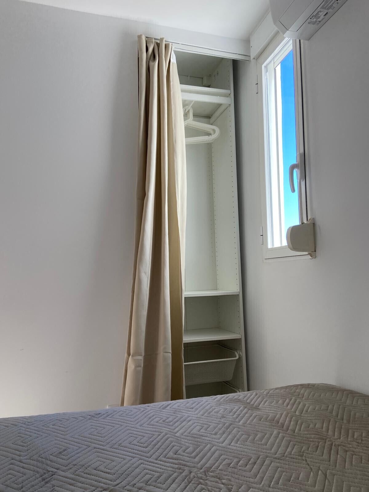 Ein Schlafzimmer mit Bett, Kleiderschrank und Fenster.