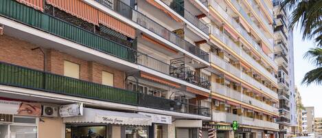 A multi-story building with balconies, a pharmacy, and various shops on the ground floor.