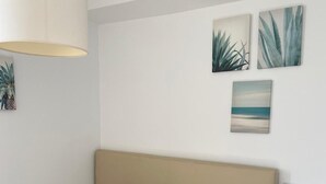 Een slaapkamer met een bed, nachtkastje en decoratieve wandkunst.