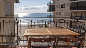 A balcony with a wooden table and chairs, overlooking a beach and ocean. - EL RACO, C-8º-16 (Cullera)