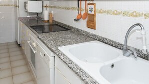 Una cocina con encimeras de granito, un lavamanos doble, lavavajillas y microondas.
