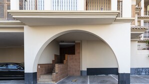 Una entrada de edificio con un arco cubierto, una escalera y un coche estacionado.