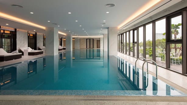Una piscina interior con zonas de descanso, ventanas amplias y un diseño moderno.