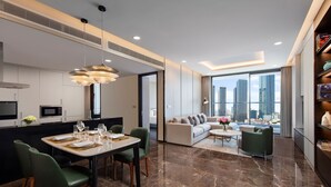 Una cocina moderna con comedor, una sala de estar con sofá y mesa de centro, y vistas a la silueta urbana.