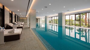 Una piscina interior moderna con zonas de descanso y amplios ventanales.