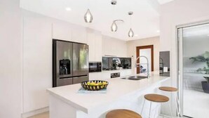 Eine moderne Küche mit Kochinsel, Barhocker und Kühlschrank.