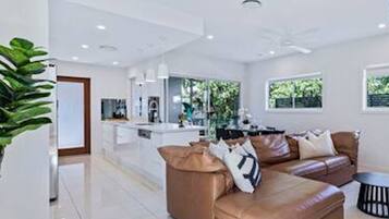 A modern living room with a brown leather sofa, a small round table, and a kitchen area in the background.