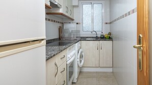 Cuina compacta amb rentadora, taulell amb rentatge i armaris.